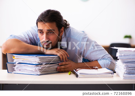 Young male employee unhappy with excessive work in the office 72168896