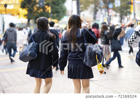 Back view of a high school girl in uniform walking in front of Shibuya station 72169324