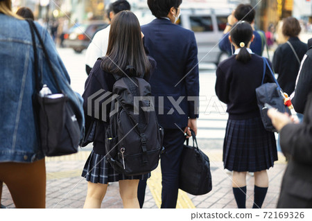 Back view of a high school girl in uniform walking in front of Shibuya station 72169326