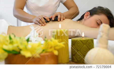 Young woman enjoying hot stone massage Young woman enjoying hot stone massage 72170004