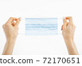 hands holding a mask, protective respiratory mask from the spread of the virus, on a white background 72170651