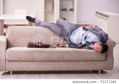 Tired young businessman coming home after working day Tired young businessman coming home after working day 72171384