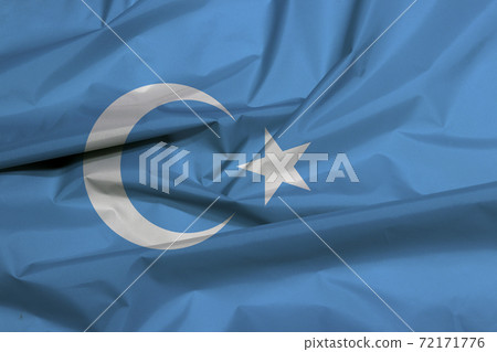 Fabric flag of East Turkestan. Crease of Uyghuristan flag background 72171776