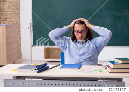 Young male teacher in front of green board Young male teacher in front of green board 72172157