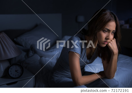 Depressed young Asian woman sitting in bed cannot sleep from insomnia. 72172191