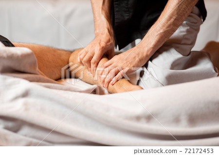 Masseur doing a deep massage to a male client 72172453