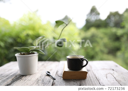 Black coffee cup with Hoya kerrii  heart shape plant with book on wooden table 72173236