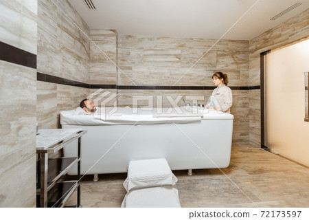 Man with a doctor at balneology room with carbon dioxide bath Man with a doctor at balneology room with carbon dioxide bath 72173597