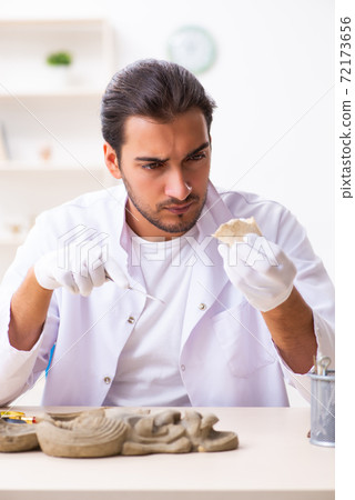 Young male archaeologist studying ancient african stonemask 72173656