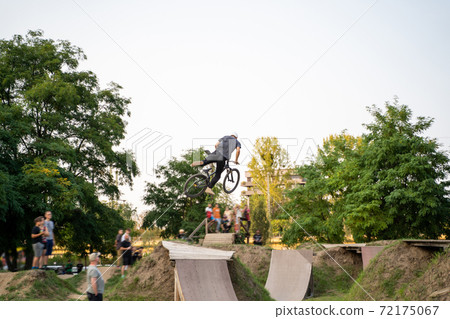 Cyclist jumping on a BMX bike outdoor near green trees on sunset. Cyclist jumping on a BMX bike outdoor near green trees on sunset. 72175067