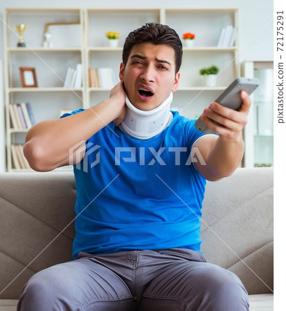 Man with neck injury watching football soccer at home 72175291