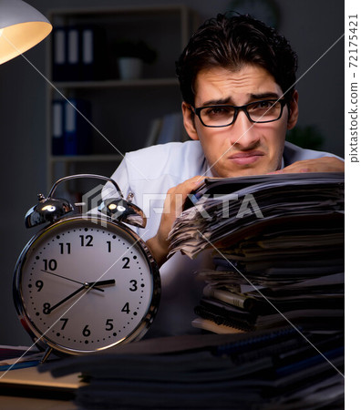 Young businessman working overtime late in office 72175421