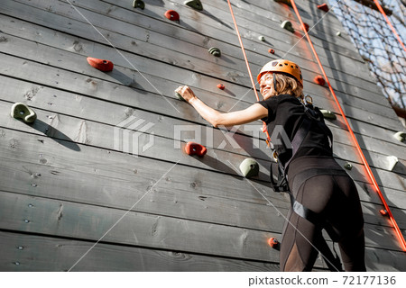 Woman climbing the wall in the park 72177136