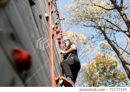 Man climbing the wall in the park Man climbing the wall in the park 72177145