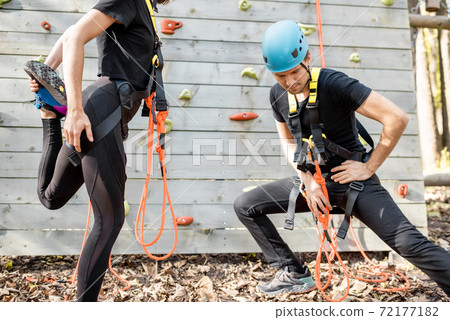 Sports couple warming up near the climbing wall in the park 72177182