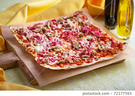 Tart flambee with tuna purple onions, cheese, green olives. Flammkuchen selective focus 72177565