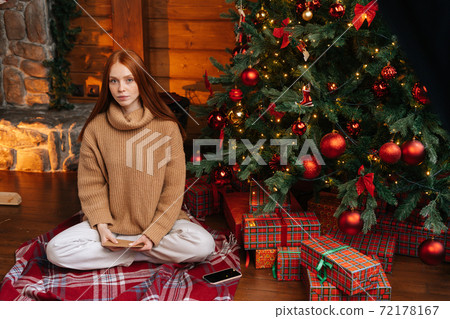 Portrait of beautiful young woman holding in hand Christmas greeting on background of Christmas tree Portrait of beautiful young woman holding in hand Christmas greeting on background of Christmas tree 72178167