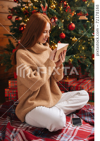 Attractive young woman getting Christmas greeting card from her beloved on background of xmas tree. Attractive young woman getting Christmas greeting card from her beloved on background of xmas tree. 72178168