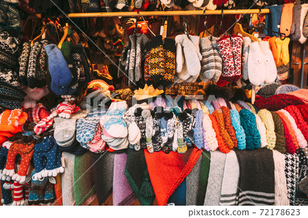 Traditional Christmas Winter Market Trading Houses With Warm Clothes, Wear And Hats. Colorful Knitted Traditional European Warm Clothes - Mittens and Scarfs. Xmas Souvenir From Europe. Traditional Christmas Winter Market Trading Houses With Warm Clothes, Wear And Hats. Colorful Knitted Traditional European Warm Clothes - Mittens and Scarfs. Xmas Souvenir From Europe. 72178623