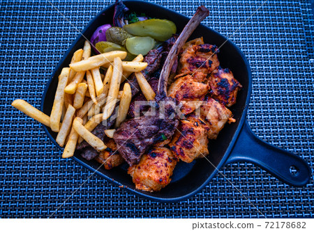 Turkish Traditional Ramadan Kebab Kofta with  fries, onion, pickles and salad in a blue plate on  blue background. 72178682