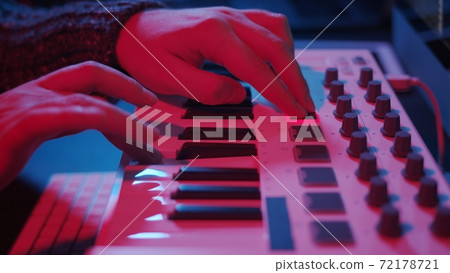 Hands using midi keyboard in home studio in night with neon lights Hands using midi keyboard in home studio in night with neon lights 72178721
