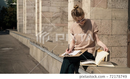 Young woman in sunglasses preparing for the exam outside Young woman in sunglasses preparing for the exam outside 72178749