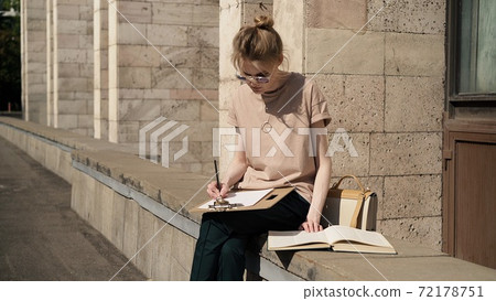 Young woman in sunglasses preparing for the exam outside, university building Young woman in sunglasses preparing for the exam outside, university building 72178751