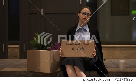 Young woman in eyeglasses in office clothes with sign job wanted 72178889