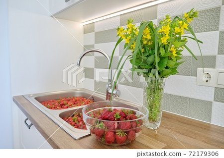 Strawberry season, washing berries in water in wash basin at home kitchen Strawberry season, washing berries in water in wash basin at home kitchen 72179306