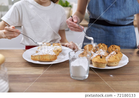 Kids sprinkling baked homemade muffins with white sugar powder Kids sprinkling baked homemade muffins with white sugar powder 72180133