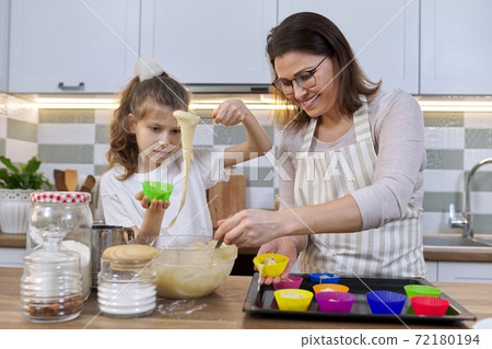 Mother and daughter cooking muffins together in home kitchen Mother and daughter cooking muffins together in home kitchen 72180194