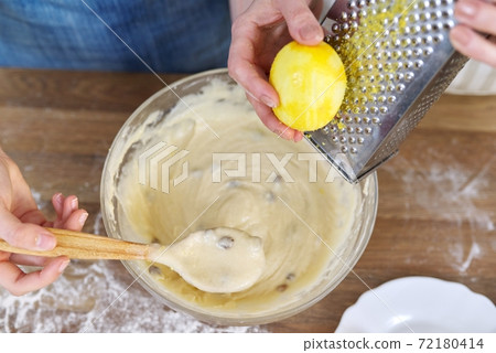 Closeup of woman rubbing lemon zest on grater, female preparing dough for muffins Closeup of woman rubbing lemon zest on grater, female preparing dough for muffins 72180414