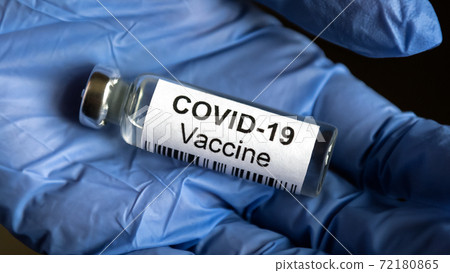 Coronavirus vaccine bottle in gloved hand close-up 72180865