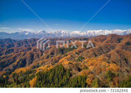 Snow-capped Hakuba mountain range and autumnal satoyama mountains seen from the origin of Ogawa village Ogawa village, Nagano prefecture (aerial view by drone) 72182848
