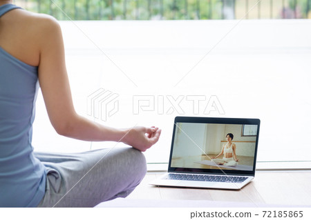 Middle-aged woman doing yoga online Middle-aged woman doing yoga online 72185865