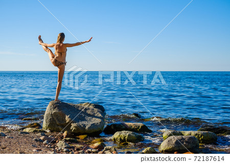 Woman standing in Hand to Toe pose near sea 72187614