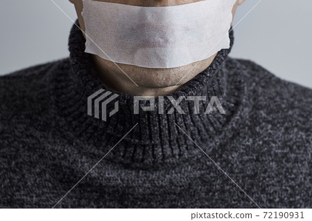 Man silenced with duct tape over his mouth on gray background. 72190931