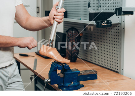 Technician checking artificial limb while at desk in workshop, adjusting it and checking for quality 72193206