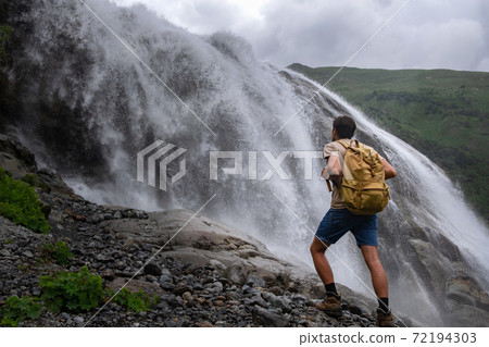 Waterfall Landscape and male Traveler enjoying waterfall view. Waterfall Landscape and male Traveler enjoying waterfall view. 72194303