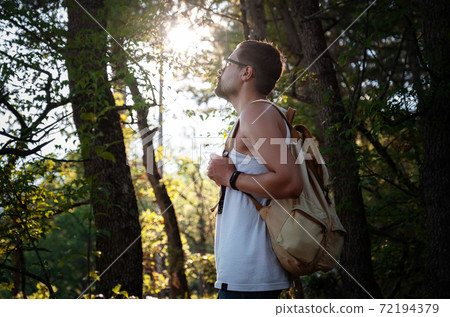Man Traveler with backpack hiking outdoor in summer sunset forest Man Traveler with backpack hiking outdoor in summer sunset forest 72194379