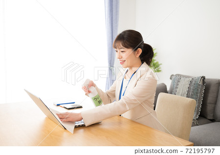 A woman who disinfects a computer and desk before work 72195797