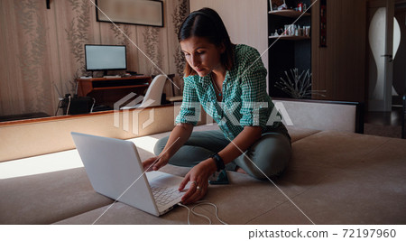 Young woman on sofa happily working on new project with laptop in home Young woman on sofa happily working on new project with laptop in home 72197960