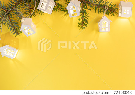 Christmas Or New Year yellow background with frame of green fir branches and luminous Xmas lights on bright yellow with copy space. Xmas decorations. Top view. Horizontal orientation. Christmas Or New Year yellow background with frame of green fir branches and luminous Xmas lights on bright yellow with copy space. Xmas decorations. Top view. Horizontal orientation. 72198048