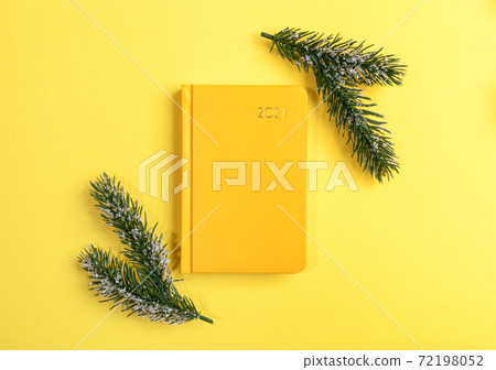 Xmas workspace. Yellow notepad-organizer on 2021 and two fir twigs on yellow. Planning for next year. Business greeting card. Top view. Minimal image. Copy space for text. Xmas workspace. Yellow notepad-organizer on 2021 and two fir twigs on yellow. Planning for next year. Business greeting card. Top view. Minimal image. Copy space for text. 72198052