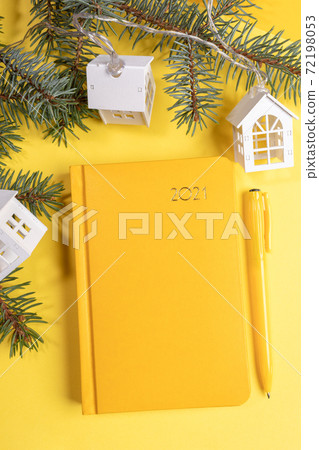 Xmas festive workspace with notepad-organizer on 2021, pen, fir branches and Xmas lights white lodges. Planning for next year. Business greeting card. Top view. Copy space. Vertical orientation. Xmas festive workspace with notepad-organizer on 2021, pen, fir branches and Xmas lights white lodges. Planning for next year. Business greeting card. Top view. Copy space. Vertical orientation. 72198053
