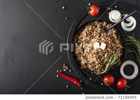 boiled quinoa with spices, oil and vegetables in a black bowl, top view boiled quinoa with spices, oil and vegetables in a black bowl, top view 72198405
