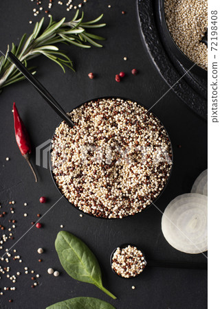 white and red quinoa grits with spices in a black bowl, top view 72198408