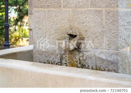 A source of drinking water lined with a hewn stone 72198701