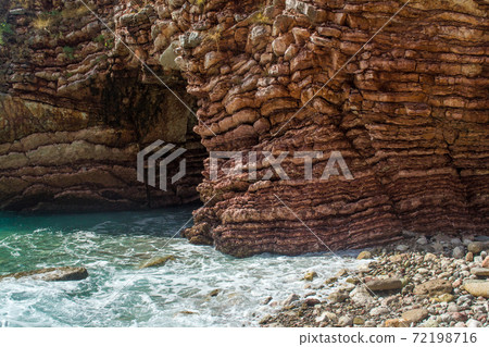 The sea view. Waves break on the stone shore. Rock and layered stone wave structure, sea foam and spray. The sea view. Waves break on the stone shore. Rock and layered stone wave structure, sea foam and spray. 72198716