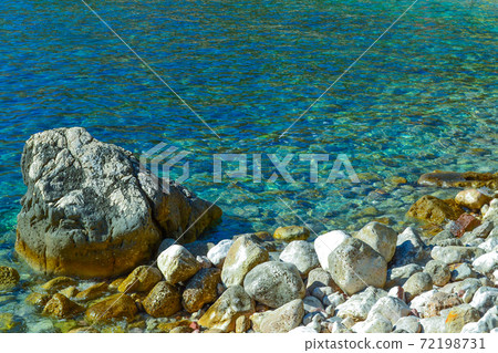 The sea view. Calm sea and large stones. Transparent water of the Adriatic Sea. Montenegro The sea view. Calm sea and large stones. Transparent water of the Adriatic Sea. Montenegro 72198731